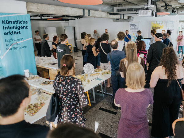 A group of guests stand in the COSMO Science Forum and listen to the speech by Gerhart Fettweis, Scientific Director of the Barkhausen Institut.