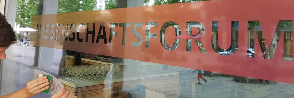 A person can be seen applying the cutting plot 'Science Forum' to the glass facade of the Kulturpalast.