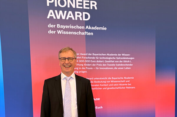 Gerhard Fettweis stands in front of a sign saying Pioneer Award and some small written text. He is smiling.