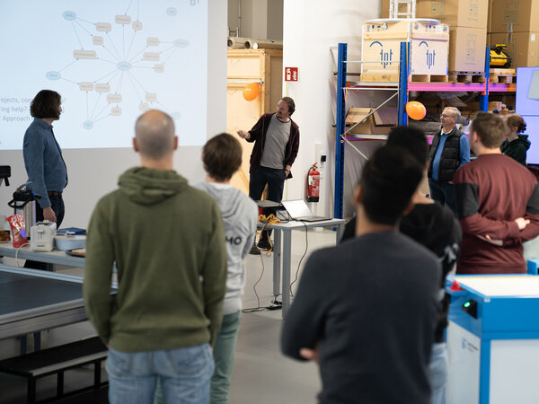 A group of people are standing in a room and interacting with each other.