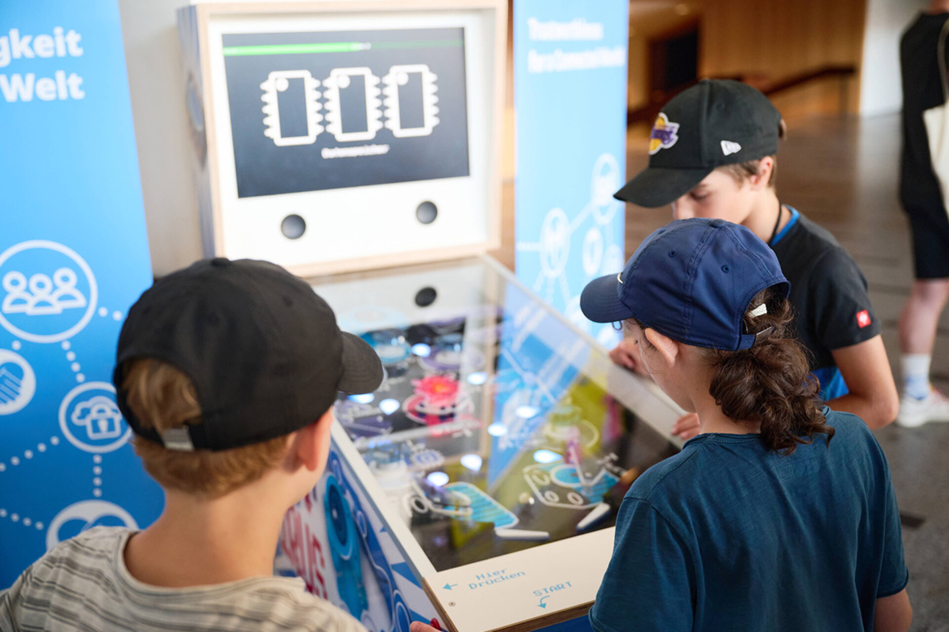 Drei Kinder spielen an einem Flipperautomaten mit digitaler Anzeige bei der Langen Nacht der Wissenschaften Dresden 2026