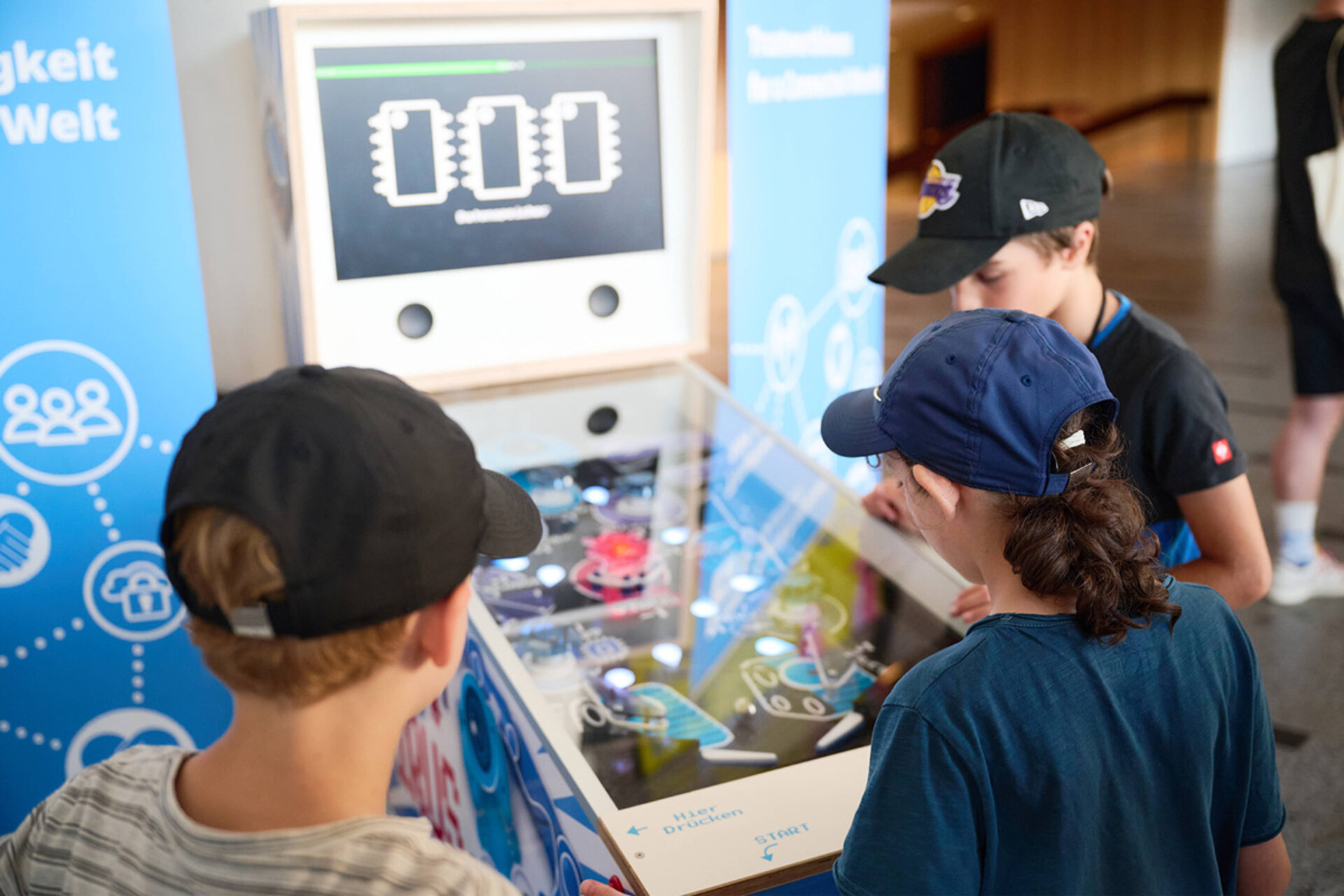 Drei Kinder spielen an einem Flipperautomaten mit digitaler Anzeige bei der Langen Nacht der Wissenschaften Dresden 2026