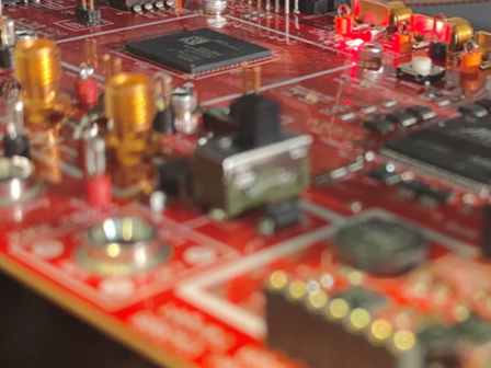 Close-up of a red circuit board with various electronic components and glowing red LEDs