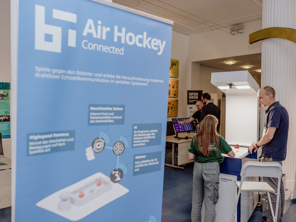 Stand des Barkhausen Instituts mit einem Schild, das den Air-Hockey-Roboter erklärt