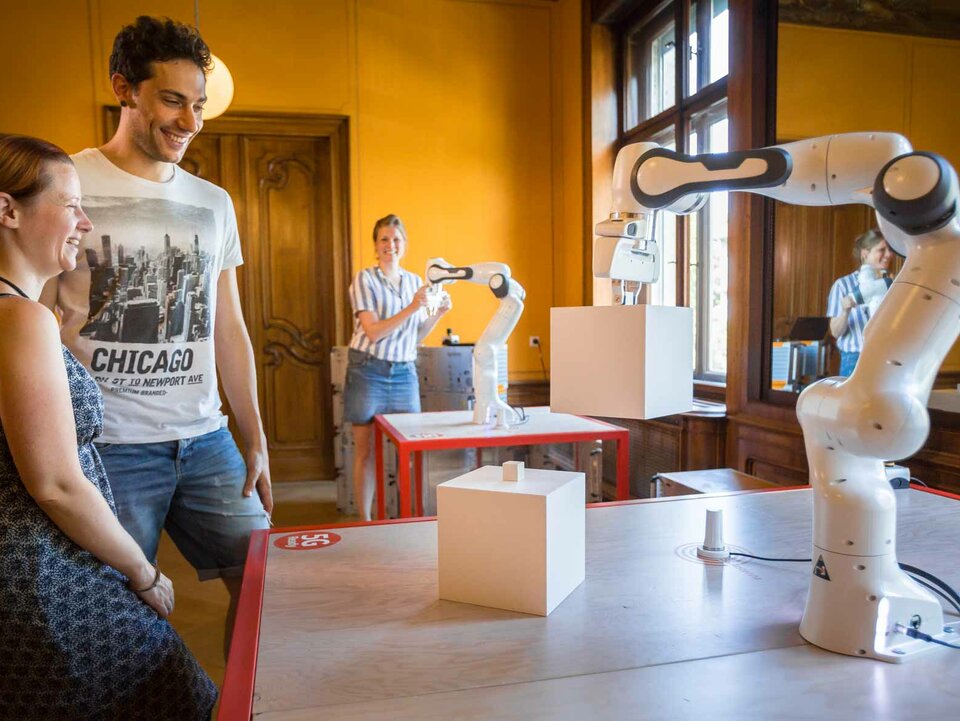 Leute in Interaktion mit dem 5G Roboter Arm