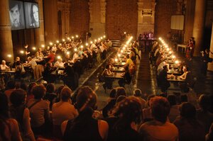people sitting pairwise in an enlighted hall for discussion