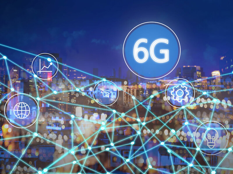 In the backgrount you see the silhouette of a city by night. In the foreground there is a net of glowing beams and some symbols e.g. a lightbulb. Then there is a big white circle with a blue filling and white text that says "6G". 