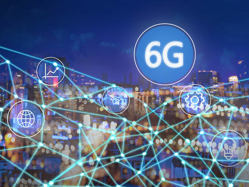 In the backgrount you see the silhouette of a city by night. In the foreground there is a net of glowing beams and some symbols e.g. a lightbulb. Then there is a big white circle with a blue filling and white text that says "6G". 