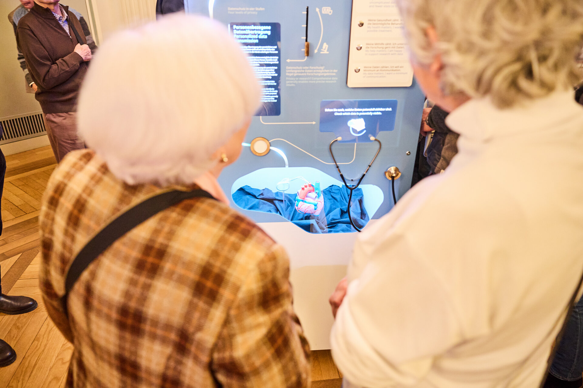 Two elderly people viewed from behind looking at a museum exhibit with a blue display and informational text