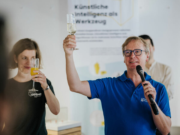 Scientific Director of the Barkhausen Institut Gerhart Fettweis and curator of the exhibition Tiphaine Cattiau hold glasses in the air and toast the opening of the exhibition.