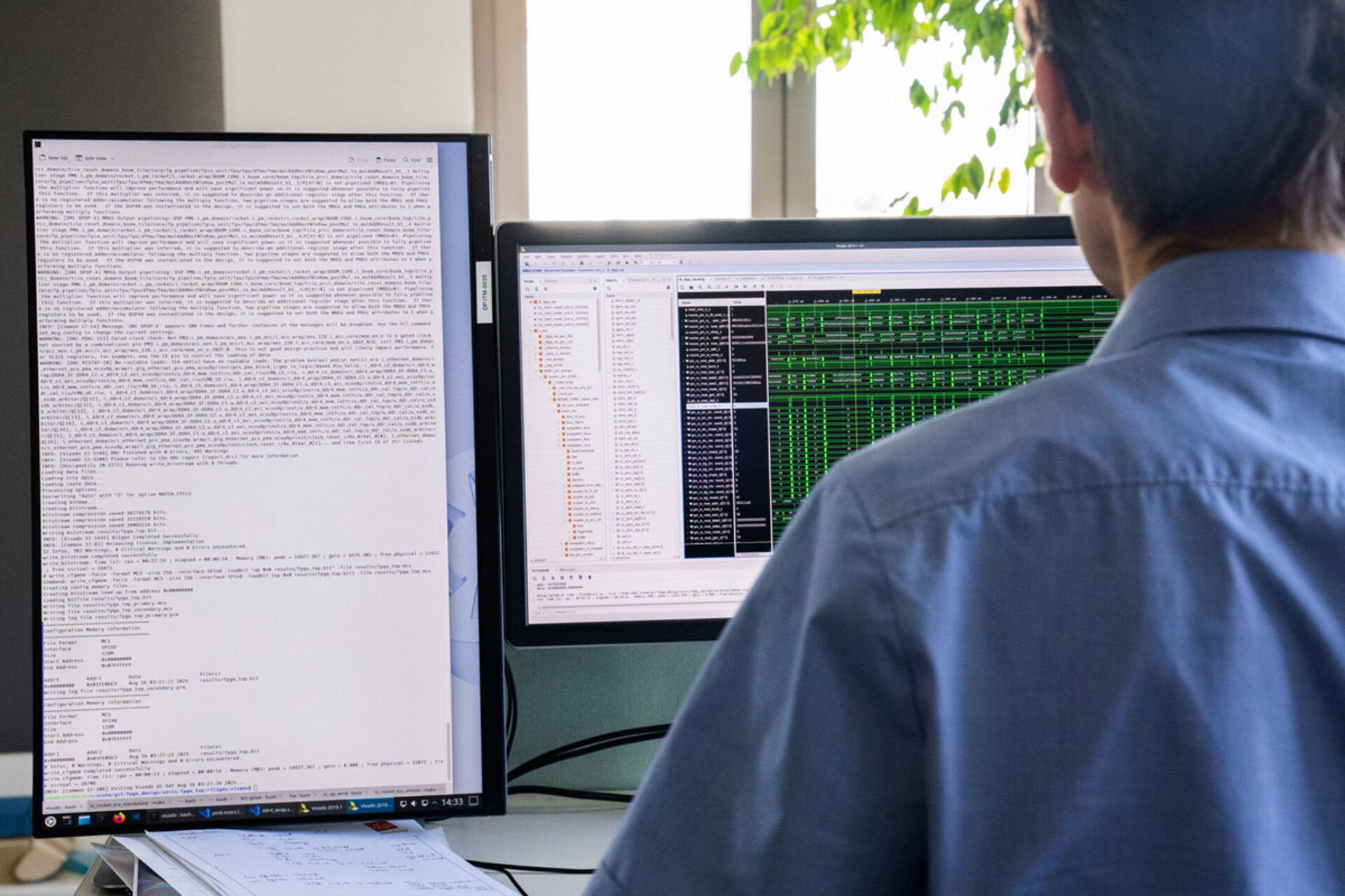 Person von hinten vor zwei Computermonitoren, einer im Hochformat mit Text und einer im Querformat mit Tabellen und Code, im Büro mit Fenster und Pflanze im Hintergrund