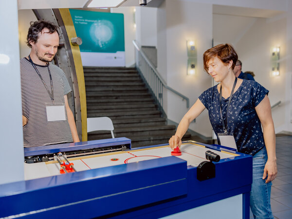Eine Frau spielt Air-Hockey gegen einen Roboter im Gerät