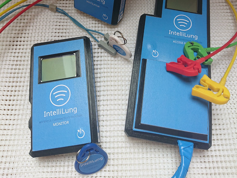 There are 3 blue devices with one screen each. It says 'IntelliLung' and the function of the device. You can also see 3 colored cables in green, red and yellow, with a clip at the end.