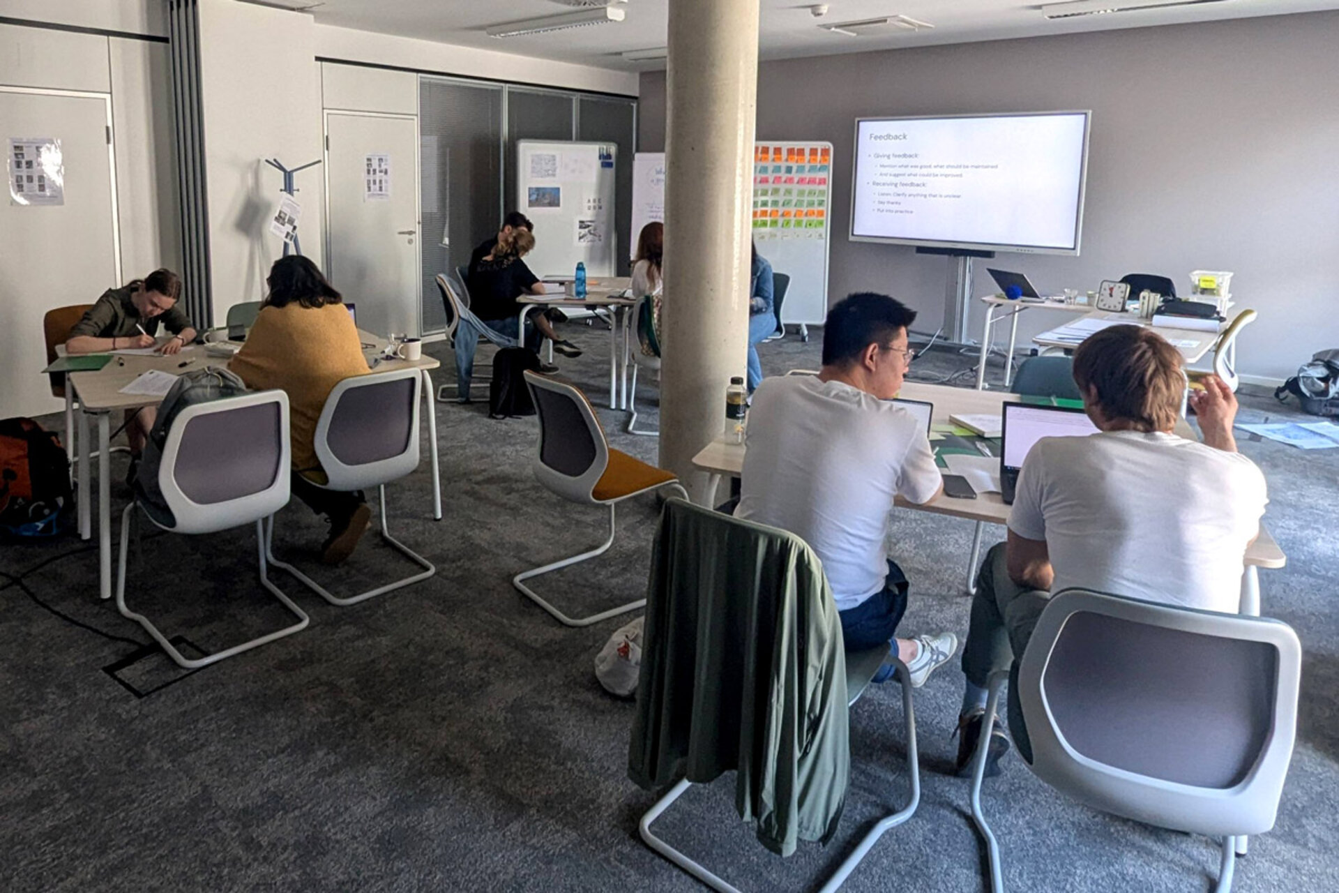 Workshop 'Besser visualisieren' with participants at tables, some working on laptops, presentation in the background.