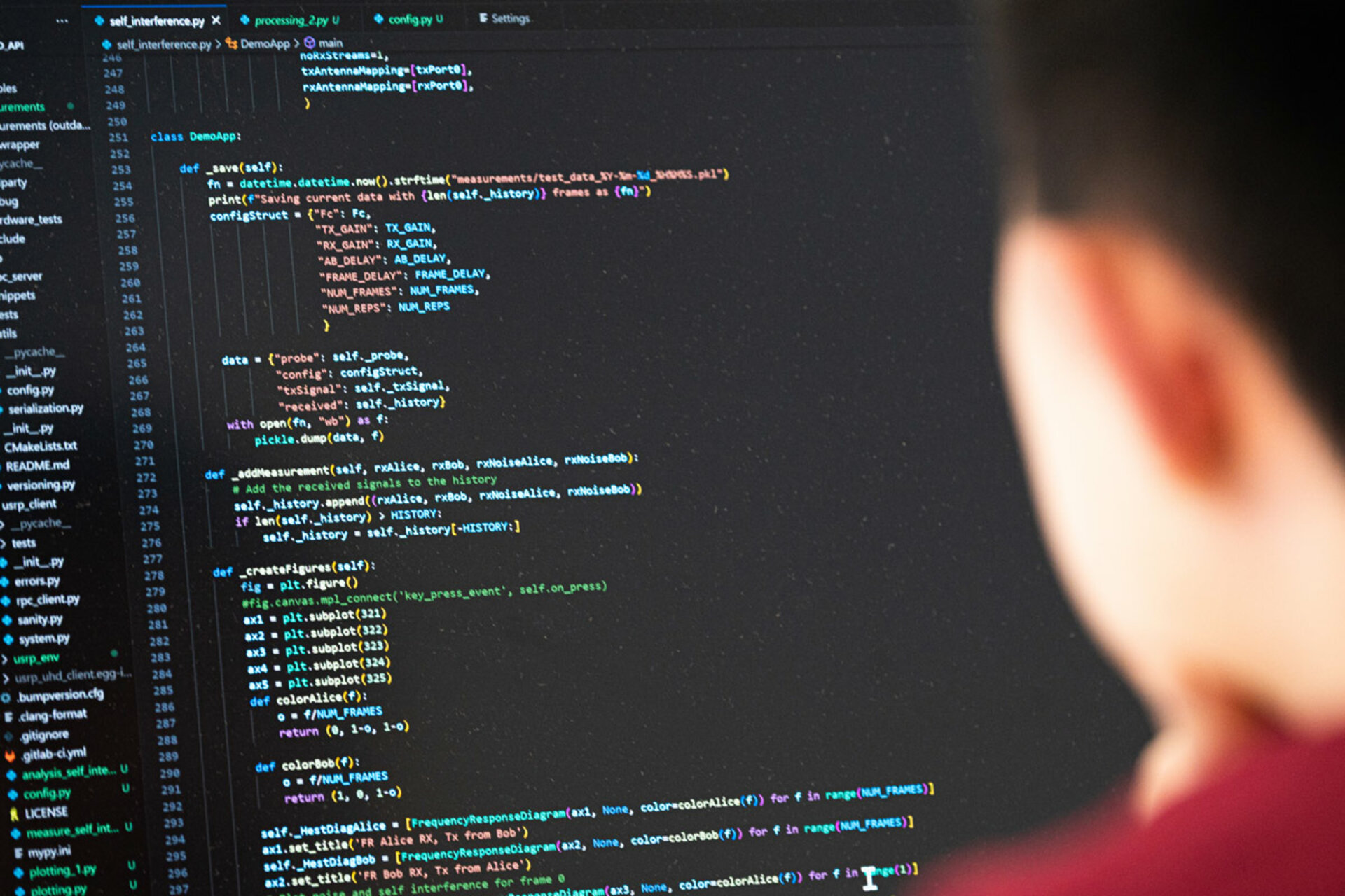Person viewed from behind looking at a computer screen displaying Python code in a dark-themed editor