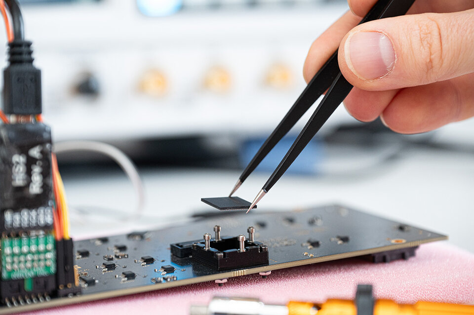 Hand setzt Masur25-Chip mit Pinzette in Sockel eines Evaluationsboards ein